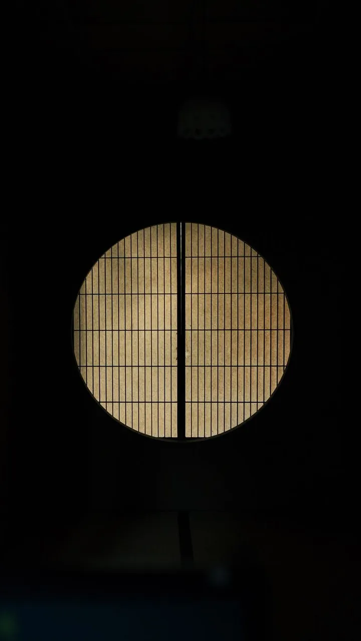 A lit circular window in a dark wall