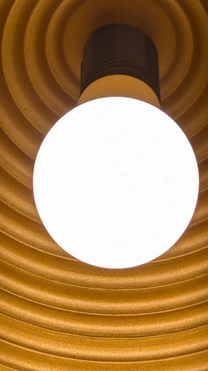 A glowing bulb inside a ribbed golden shade